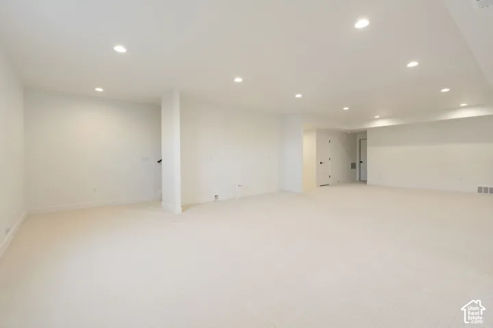 Spacious room featuring neutral carpeting, recessed lighting, and white walls