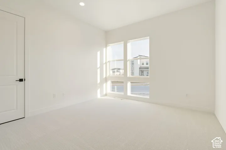 Recessed ceiling light, paneled door with matte black hardware, large multi-pane windows, light-toned wall-to-wall carpeting, and white painted walls
