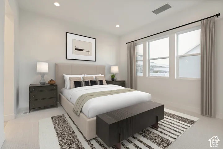 Recessed lighting illuminates a space featuring light-colored carpeting, multiple windows with neutral drapes, and a fabric-upholstered bed frame