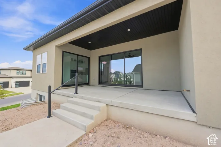 Expansive covered patio featuring concrete flooring, a black slatted ceiling, recessed lighting, and a metal handrail