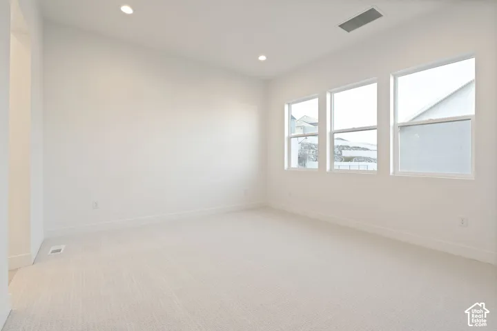 Recessed lighting, light-toned carpeting, white walls, and multiple windows