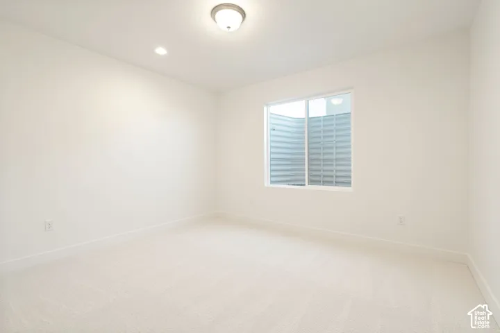 Recessed lighting, flush-mount ceiling light, white carpet, white walls, and a sliding window