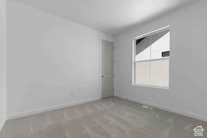 Neutral gray carpet, white walls, and a single window with a white frame