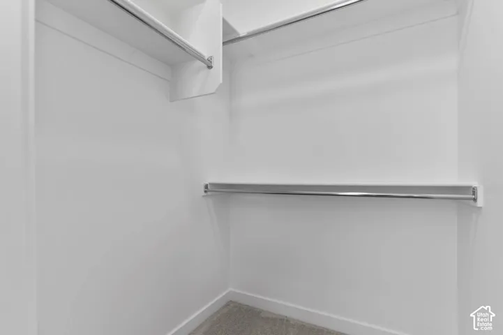 White-painted interior with chrome hanging rods, integrated shelving, and carpet flooring
