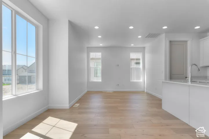 Open-concept living space with light wood-finish flooring, white walls, recessed ceiling lighting, and large grid-pattern windows