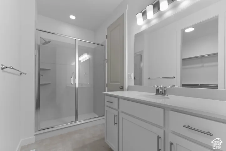 Glass-enclosed shower with built-in shelving, vanity with integrated sink, chrome faucet, and overhead lighting fixture