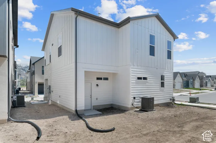 White exterior siding featuring vertical and horizontal panels, multiple windows, and a side-entry door