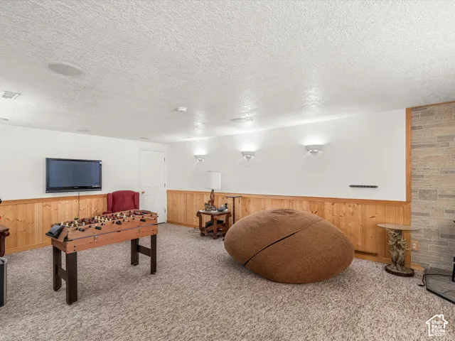 Recessed ceiling lighting, wood paneling, wall-mounted sconce lighting, carpet flooring, and stone accent wall