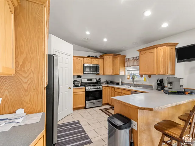 Kitchen featuring wood cabinetry, stainless steel appliances, a tile floor, and recessed lighting