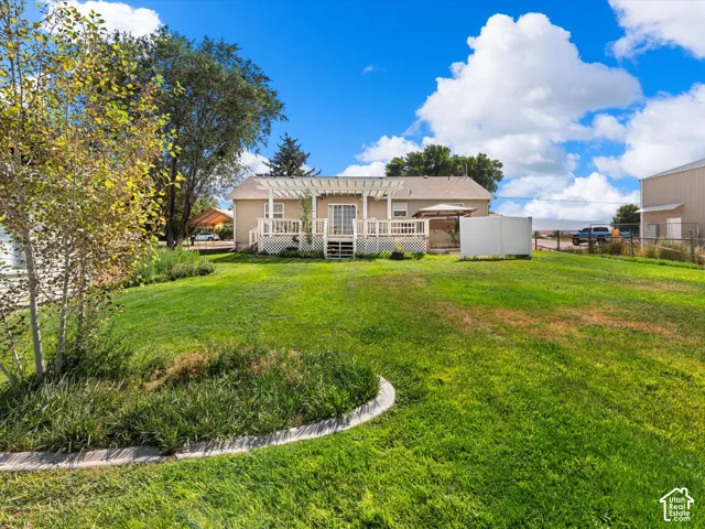 Expansive backyard featuring a manicured lawn, established trees, and a concrete-edged garden bed
