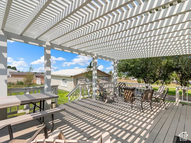 Expansive outdoor deck featuring a slatted pergola, white wood decking, and white wood railings