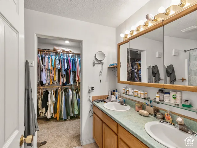 Double vanity with dual sinks, overhead vanity lighting, and a large mirror with integrated medicine cabinets