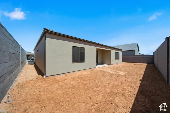 Expansive exterior featuring stucco siding, a covered patio, and perimeter block fencing