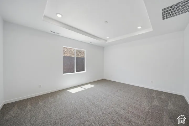 Recessed lighting, tray ceiling, carpeted flooring, white walls, and a large window