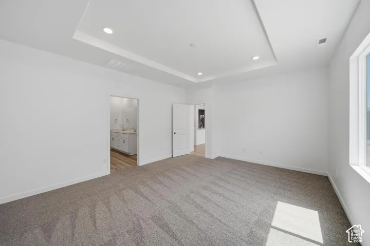 Recessed lighting, tray ceiling, carpeted flooring, window, and white walls