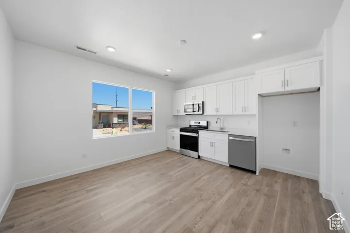 Open-concept living space with wood-finish flooring, recessed lighting, and a large window