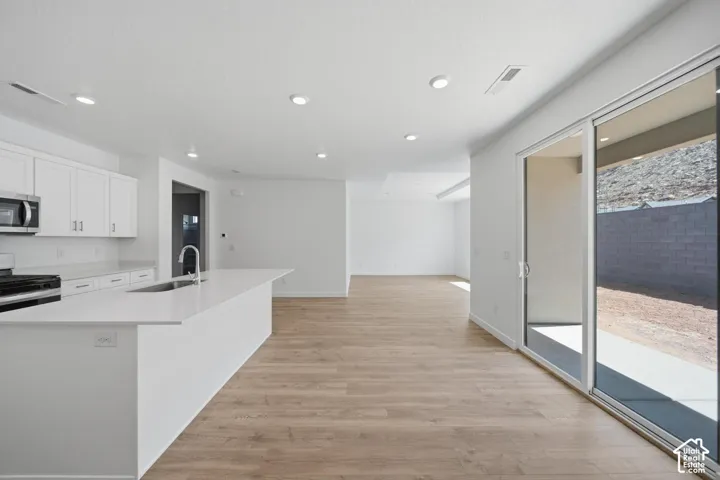 Open-concept layout with wood-finish flooring, recessed lighting, and white cabinetry