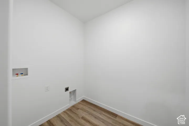 Dedicated laundry area featuring wood-finish flooring, white walls, and built-in utility connections