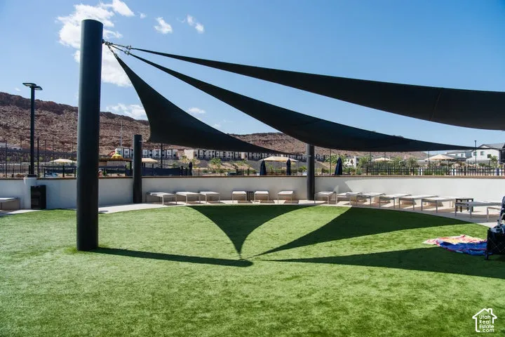 Expansive artificial turf area with multiple shade sails, a low retaining wall, and integrated path lighting