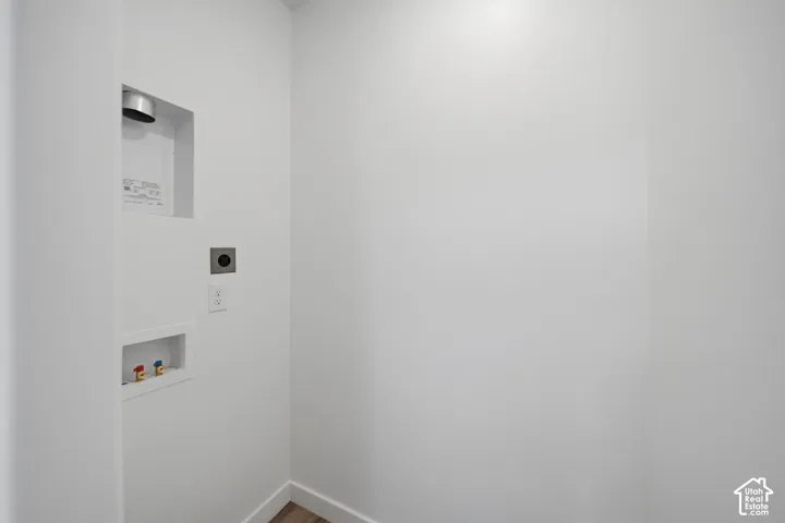 Laundry area with white walls and wood-finish flooring