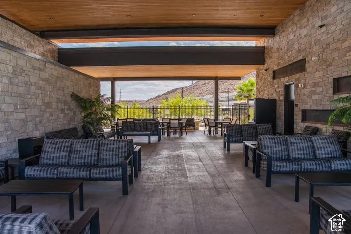 Expansive covered patio featuring stone-clad walls, a wood-finish ceiling, and concrete flooring