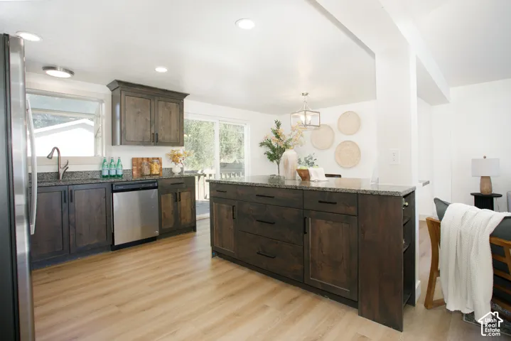 Wood-finish flooring, dark wood cabinetry, granite countertops, stainless steel appliances, and recessed lighting