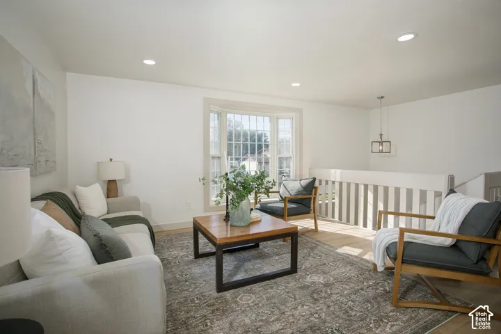 Recessed ceiling lighting, wood-finish flooring, bay window, light-toned walls, and a suspended ceiling fixture