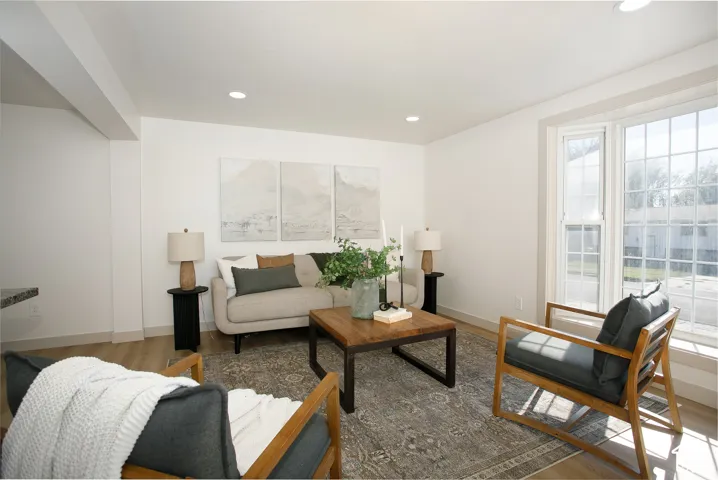 Recessed lighting illuminates wood-finish flooring and a bay window