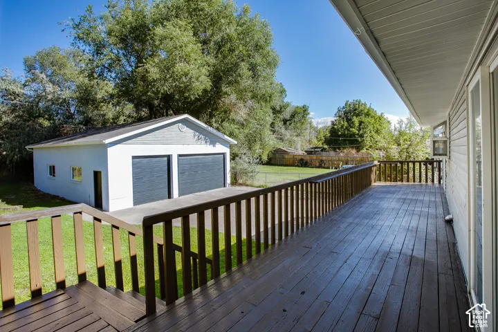 Expansive wood deck with a full railing system, overlooking a detached two-car garage with overhead doors