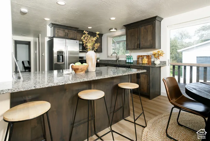 Kitchen featuring granite countertops, dark wood-finish cabinetry, stainless steel appliances, and wood-finish flooring
