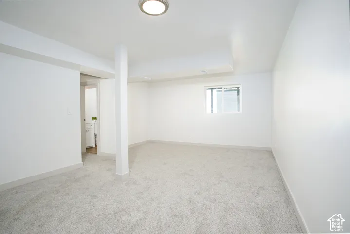 Recessed lighting illuminates a spacious room featuring light-toned carpeting and a window