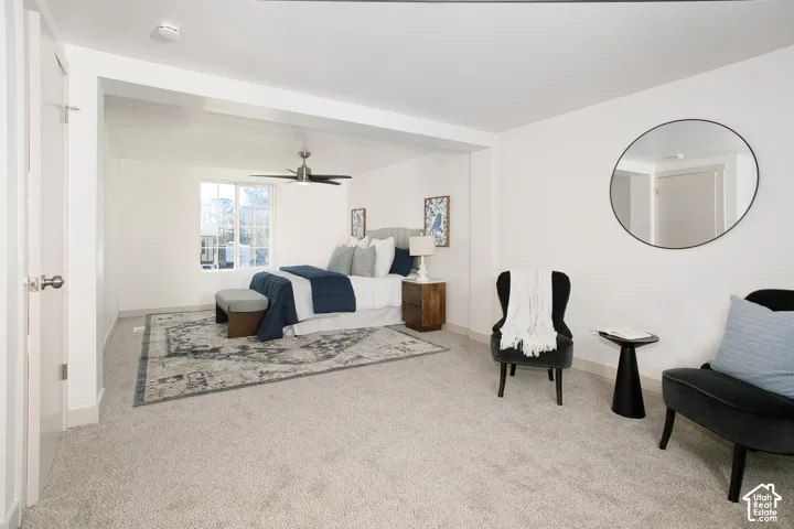 Expansive room featuring light-toned carpet, a ceiling fan with integrated lighting, a large window, and a built-in architectural recess