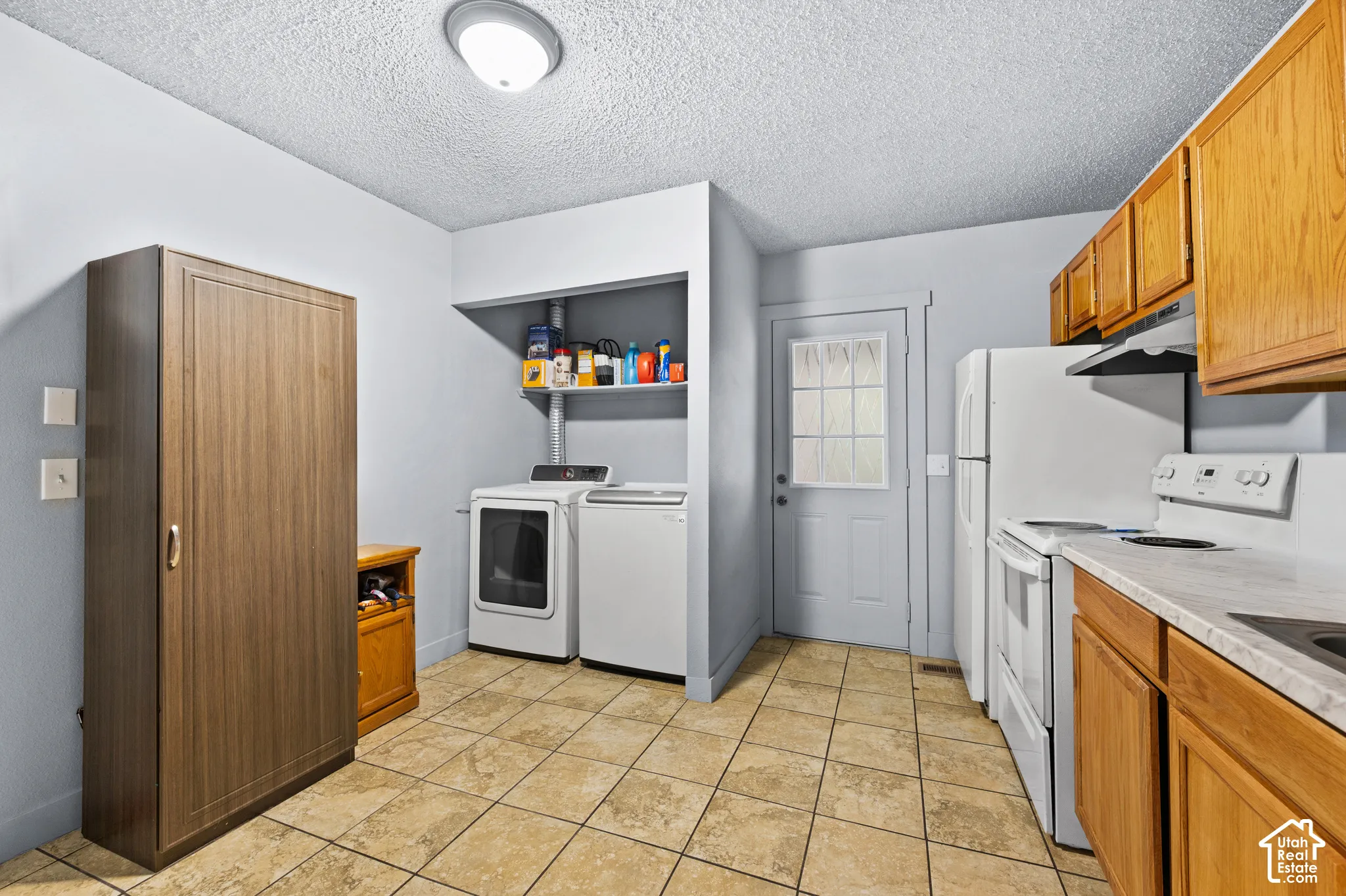 Tiled flooring, wood-finish cabinetry, white appliances, built-in shelving, and a paneled door