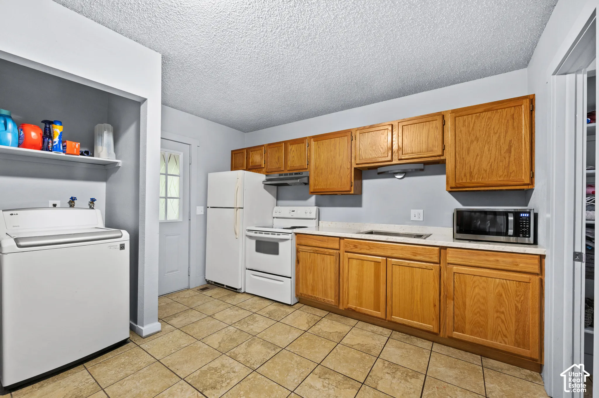 Kitchen with wood-finish cabinetry, light-toned countertops, and tile flooring