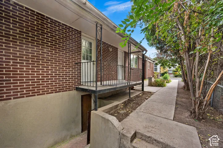 Brick exterior with a covered porch, wrought iron railing, and concrete walkway