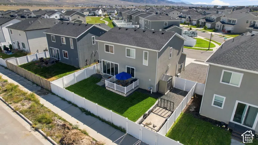 Rear elevation with a white privacy fence, an elevated deck, and a manicured lawn