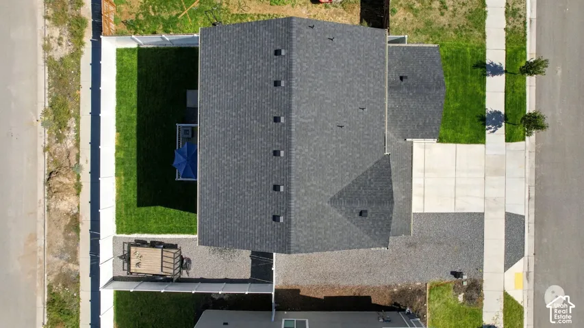 Asphalt shingle roof, concrete driveway, concrete sidewalk, fenced backyard with lawn, gravel side yard