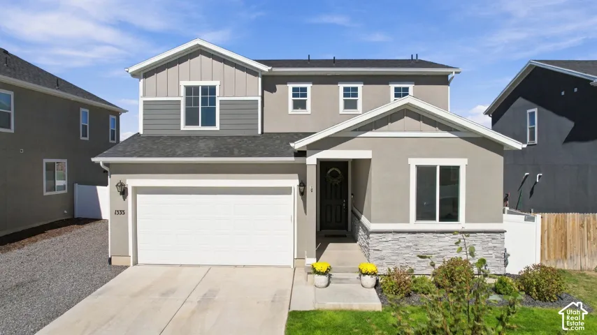 Two-story residence featuring a two-car garage, stone facade accents, and a covered entry