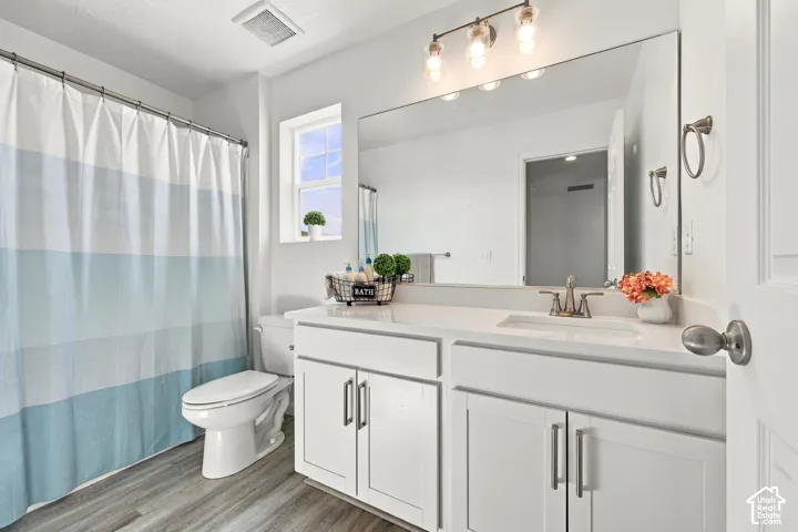 White vanity with dual doors and drawers, undermount sink, and wall-mounted light fixture