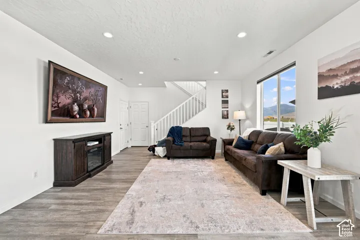 Spacious room with wood-finish flooring, white walls, and recessed lighting