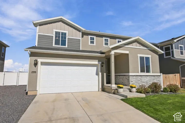 Multi-level residence featuring a two-car garage, partial stone veneer, and a covered entry