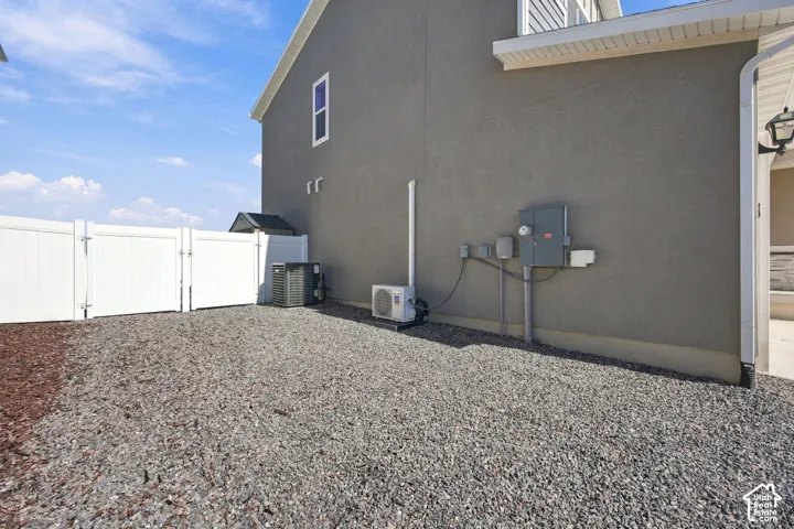 Gravel side yard with a white vinyl fence and stucco exterior