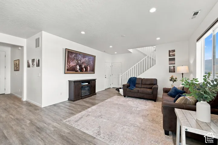 Open-concept living area featuring wood-finish flooring, recessed lighting, and large windows