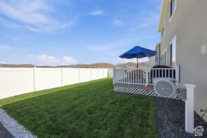 Expansive green lawn with a privacy fence, complemented by a raised deck featuring white railings and lattice skirting