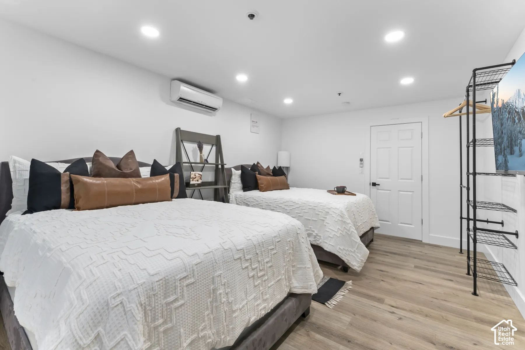 Recessed lighting illuminates the room, featuring wood-finish flooring and a built-in split air conditioning unit