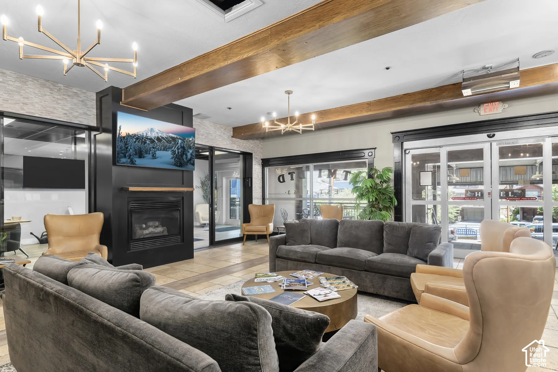 Stone-clad accent wall with wood-finish ceiling beams, tile flooring, and integrated fireplace with mantel