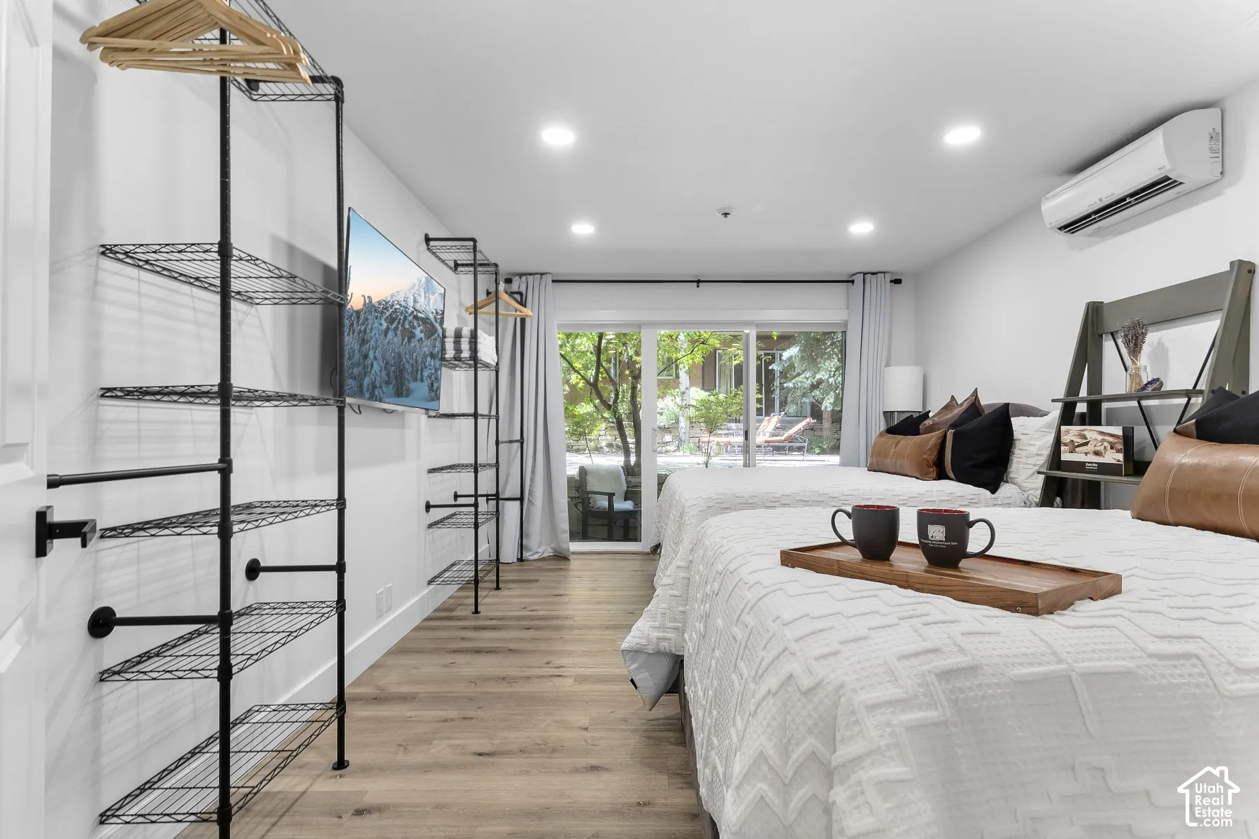 Wood-finish flooring, recessed lighting, and a wall-mounted air conditioning unit
