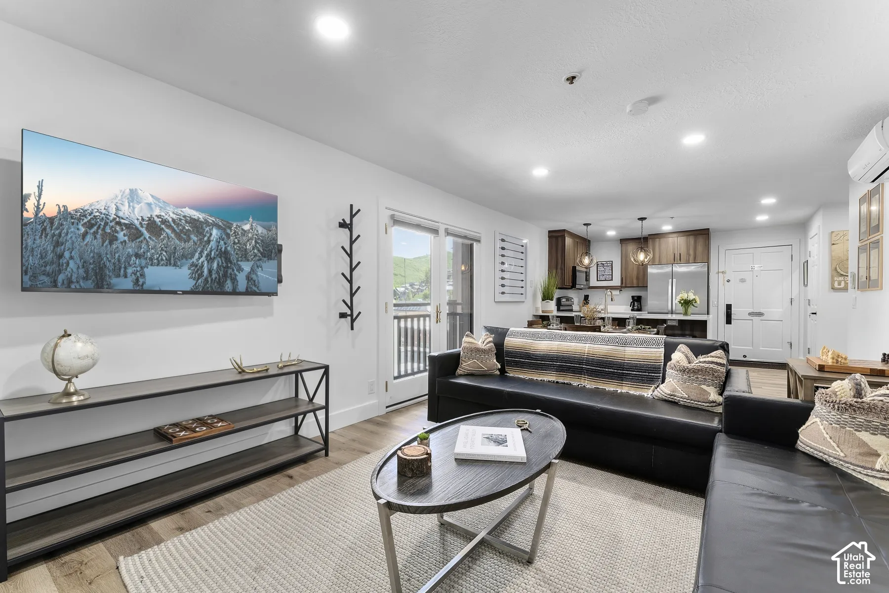 Open-concept living area featuring wood-finish flooring, recessed lighting, and a kitchen with wood cabinetry, stainless steel appliances, and pendant lighting
