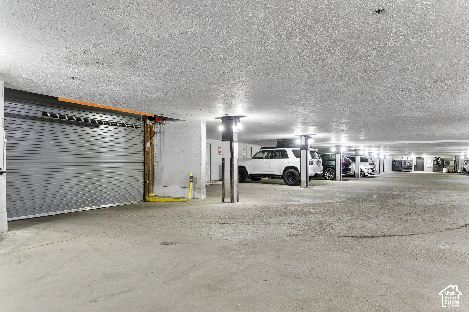 Secure underground parking garage with concrete flooring and ample overhead lighting