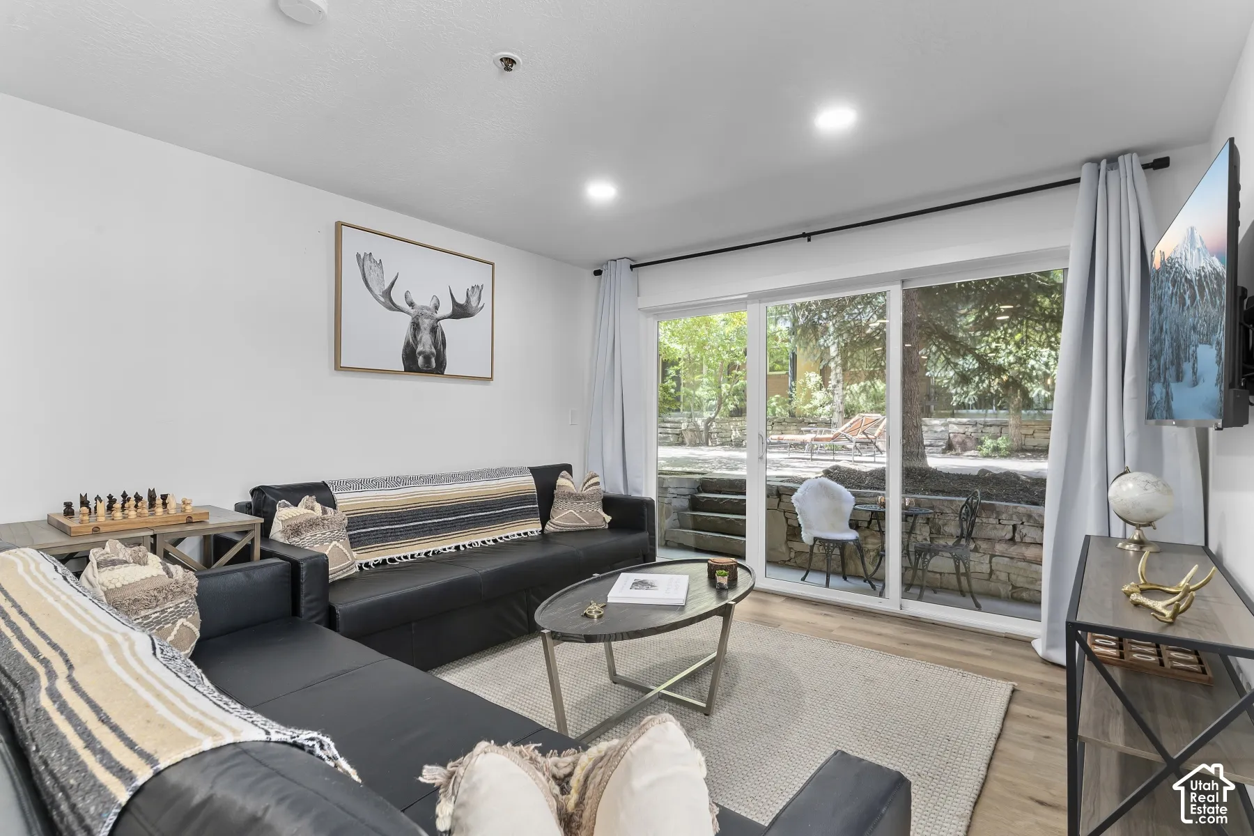 Recessed lighting, wood-finish flooring, white walls, and a sliding glass door opening to an outdoor patio
